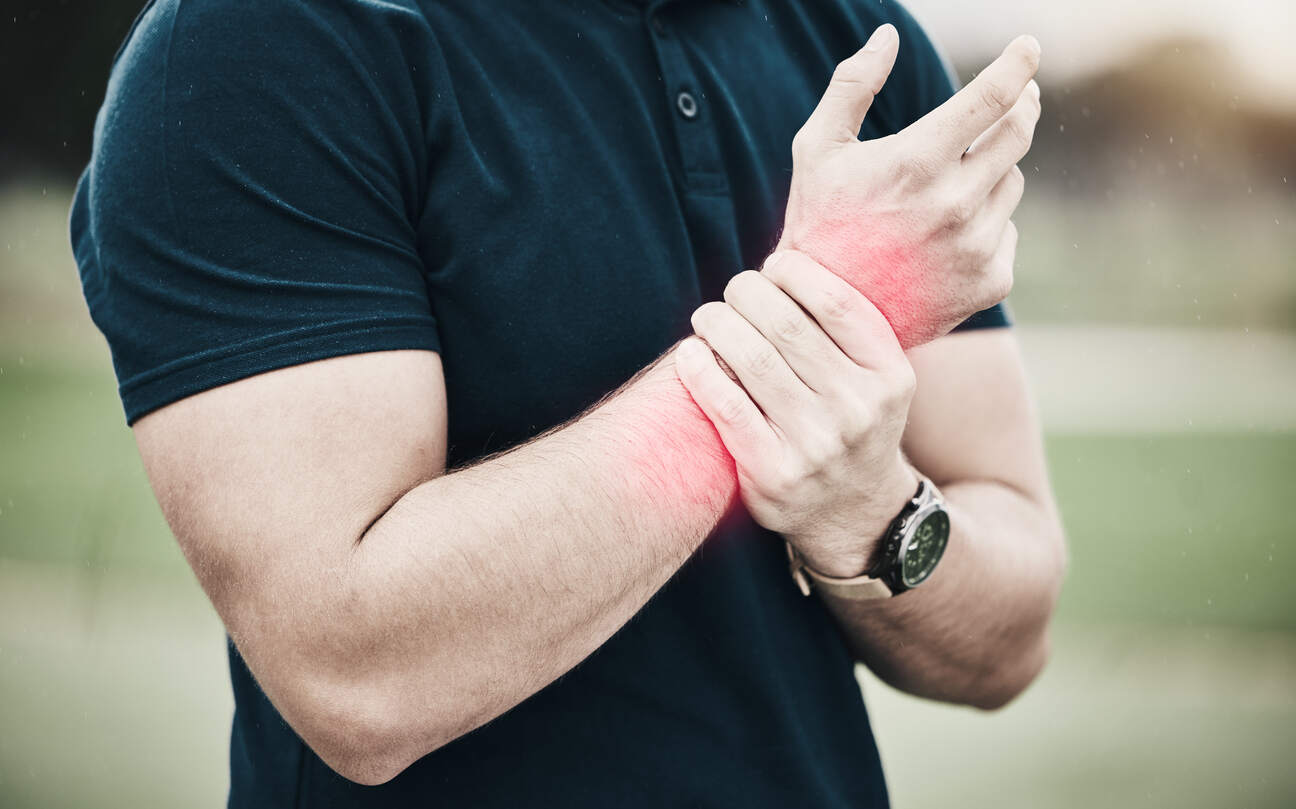 A man grimaces, holding his wrist in pain, highlighting common wrist injuries from car accidents.