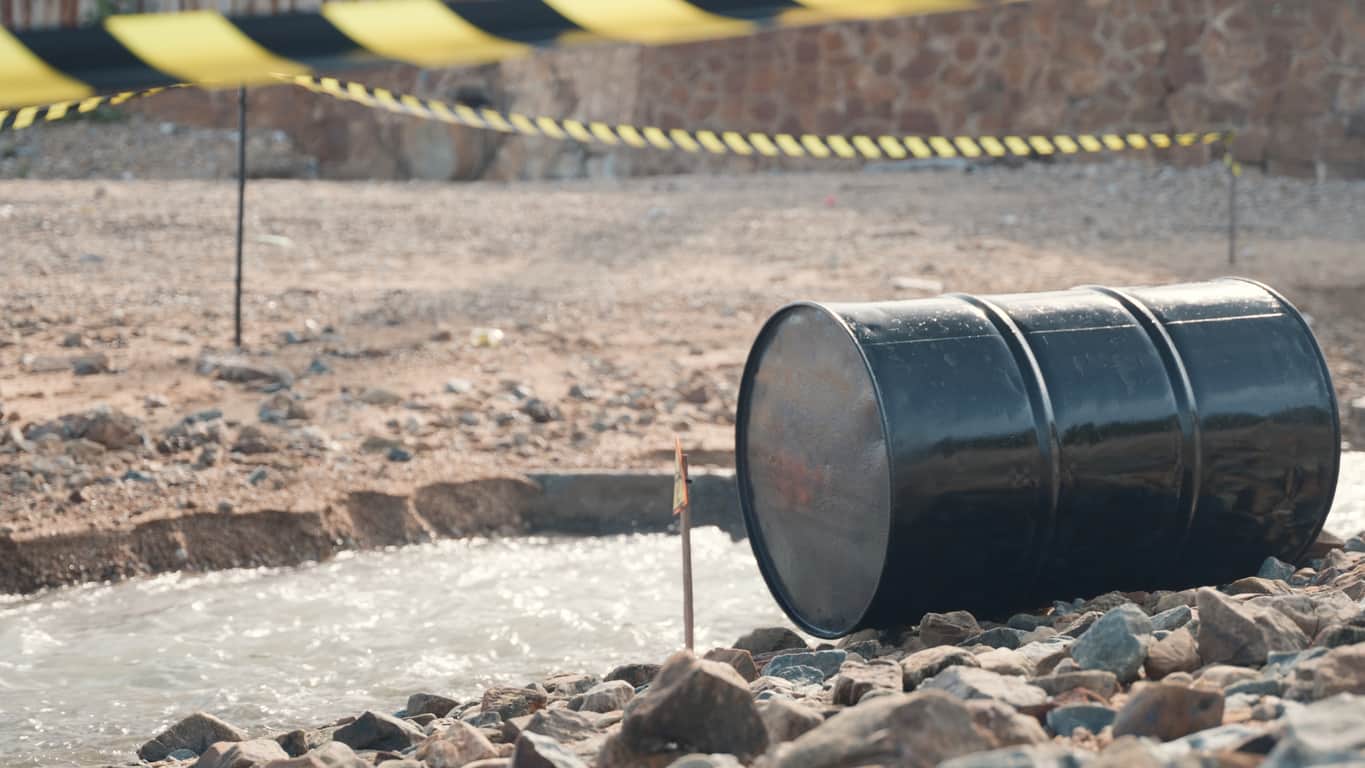A barrel on the ground beside a stream, highlighting concerns related to the Oil Pollution Act and environmental protection.