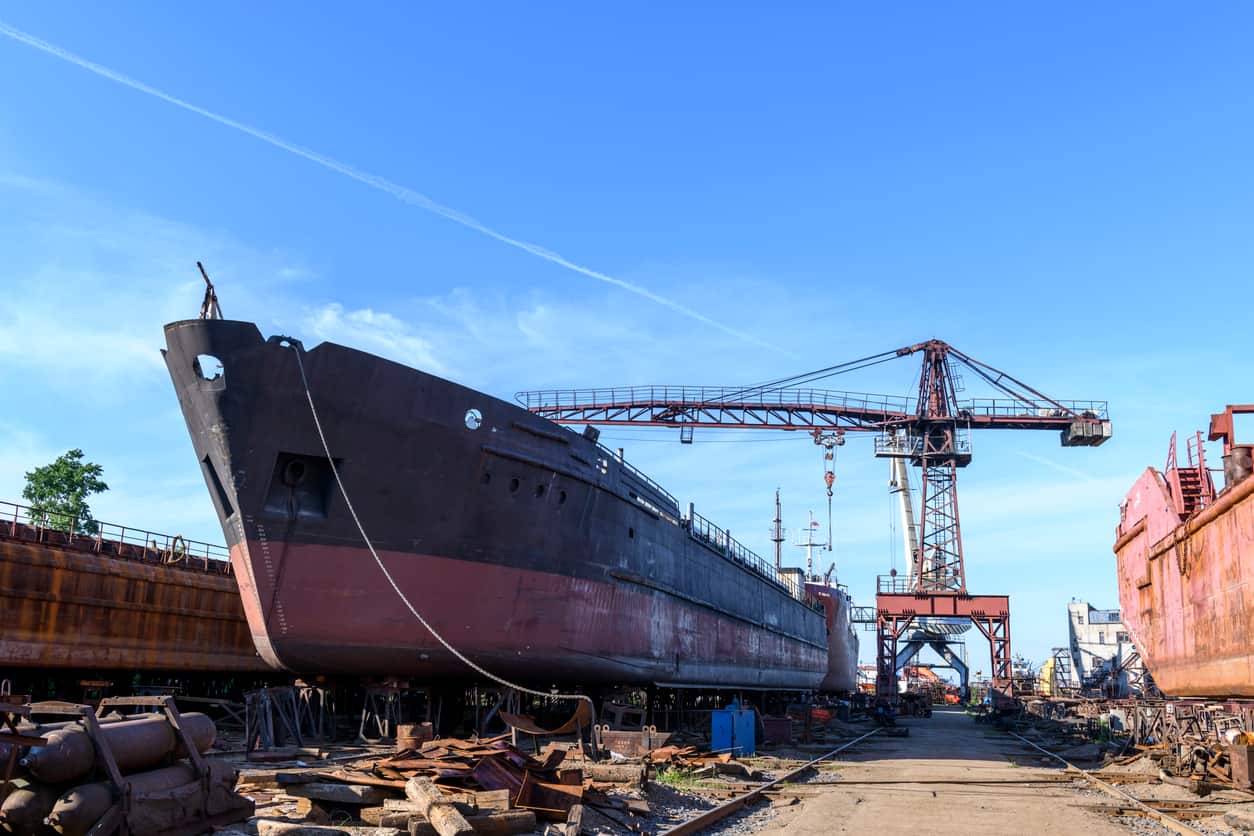 A shipyard with large vessels and cranes, where workers may face asbestos exposure due to the materials used in shipbuilding and repairs.