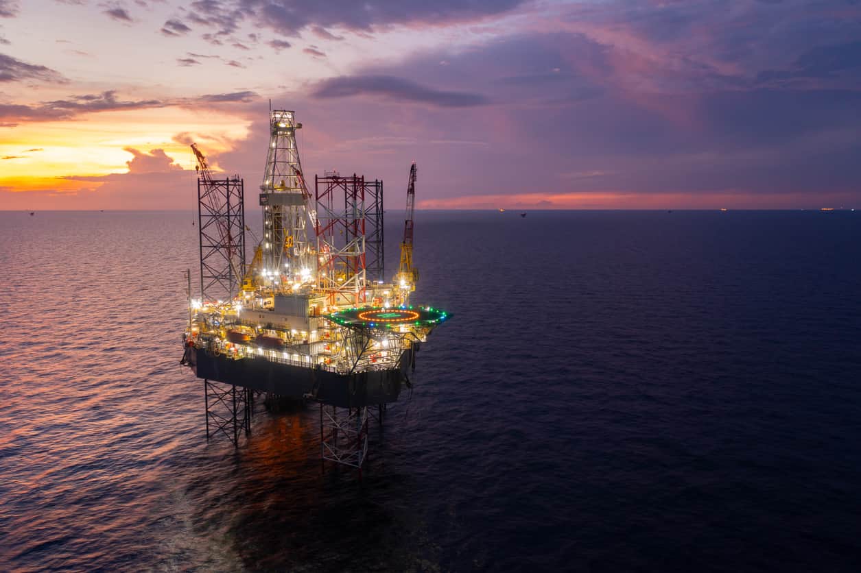 An oil rig at sea during sunset, symbolizing the dangers and risks faced by workers on offshore oil rigs.