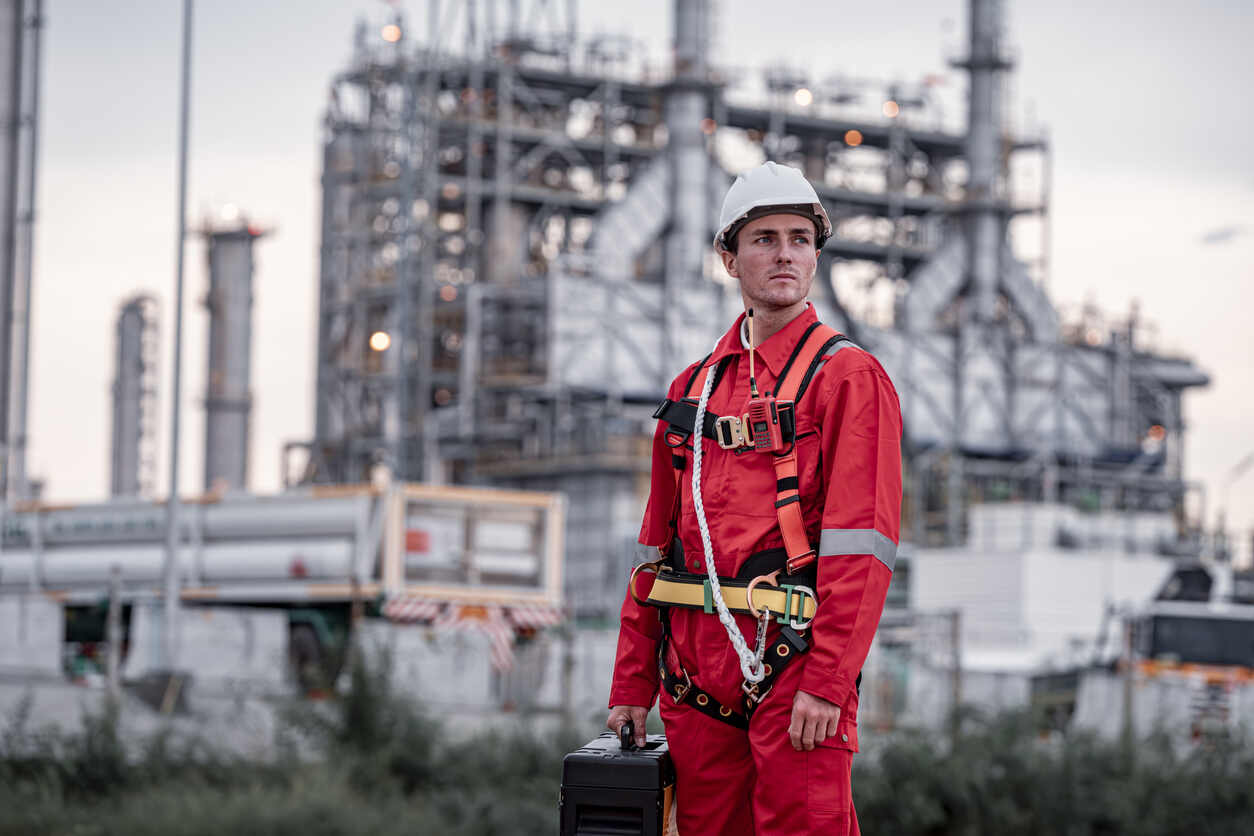 Industrial worker in oil and gas facility exposed to visible gas fumes, wearing safety helmet and mask, pipes and refinery background, realistic lighting, toxic exposure concept