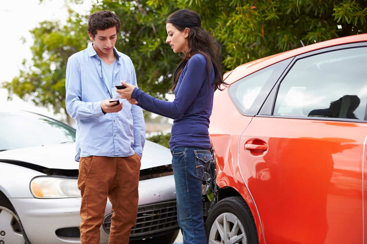 Teen drivers exchanging information after a car accident caused by reckless driving